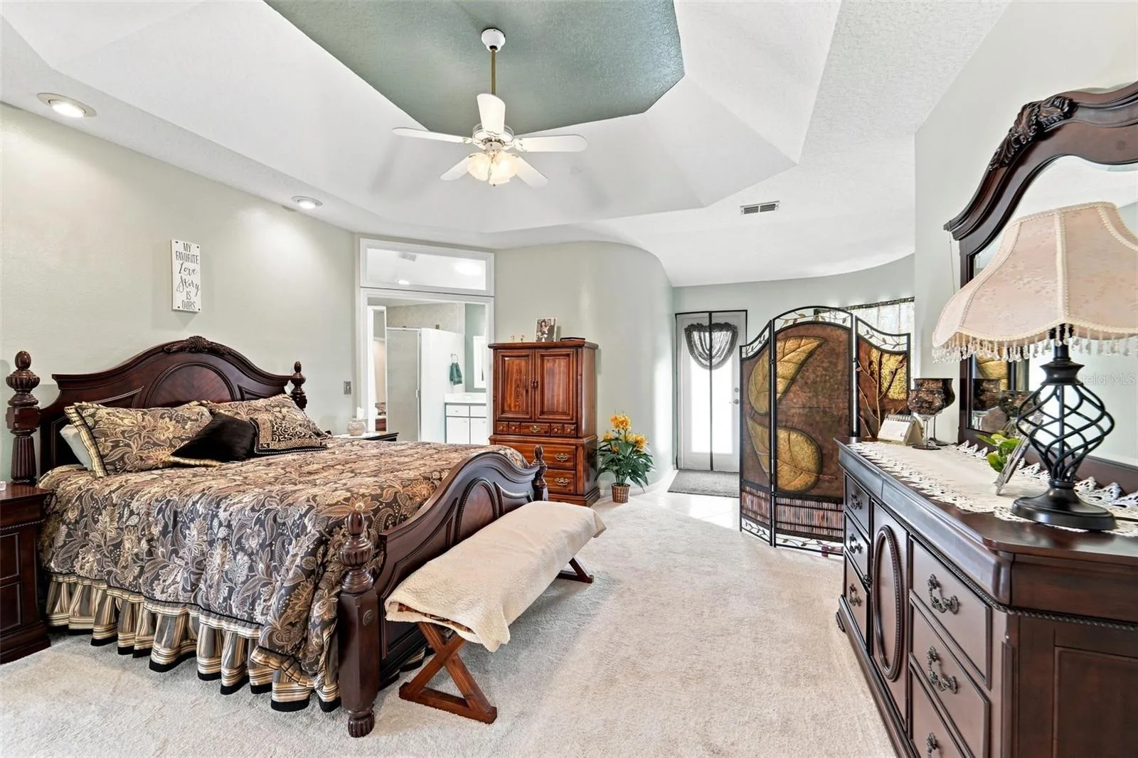 Large primary bedroom with ensuite bathroom, walk-in closet and a convenient sitting area near the pool deck entrance.