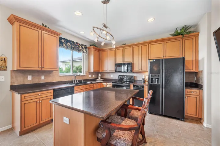 The kitchen is sunny &amp; bright . Surrounded by solid wood cabinetry with plenty of storage , granite countertops, a breakfast Bar , along with a view of Island Lake and the 15th hole