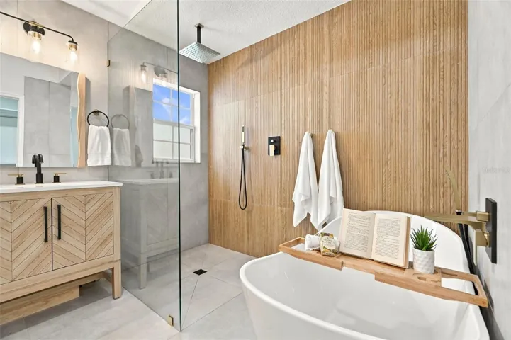 A frameless glass walk-in shower with a rainfall shower head system, a standalone soaking tub, and dual vanity sinks.