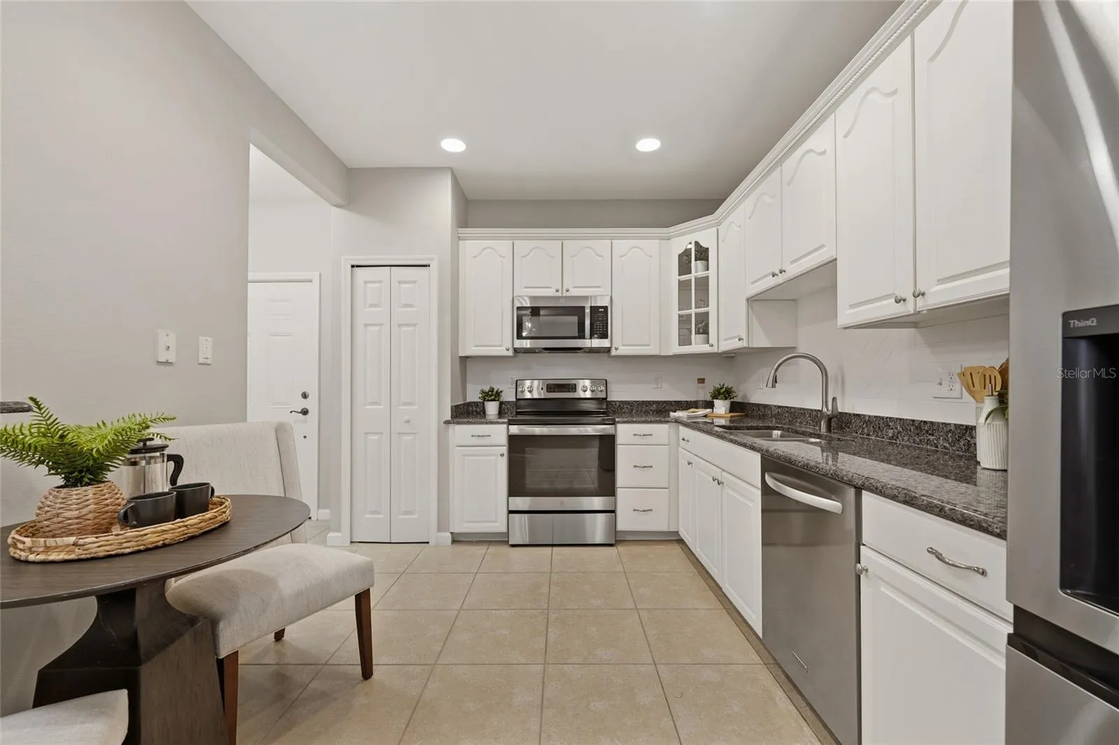 Well-appointed kitchen with white cabinetry, granite countertops, stainless-steel appliances and a casual dining area.