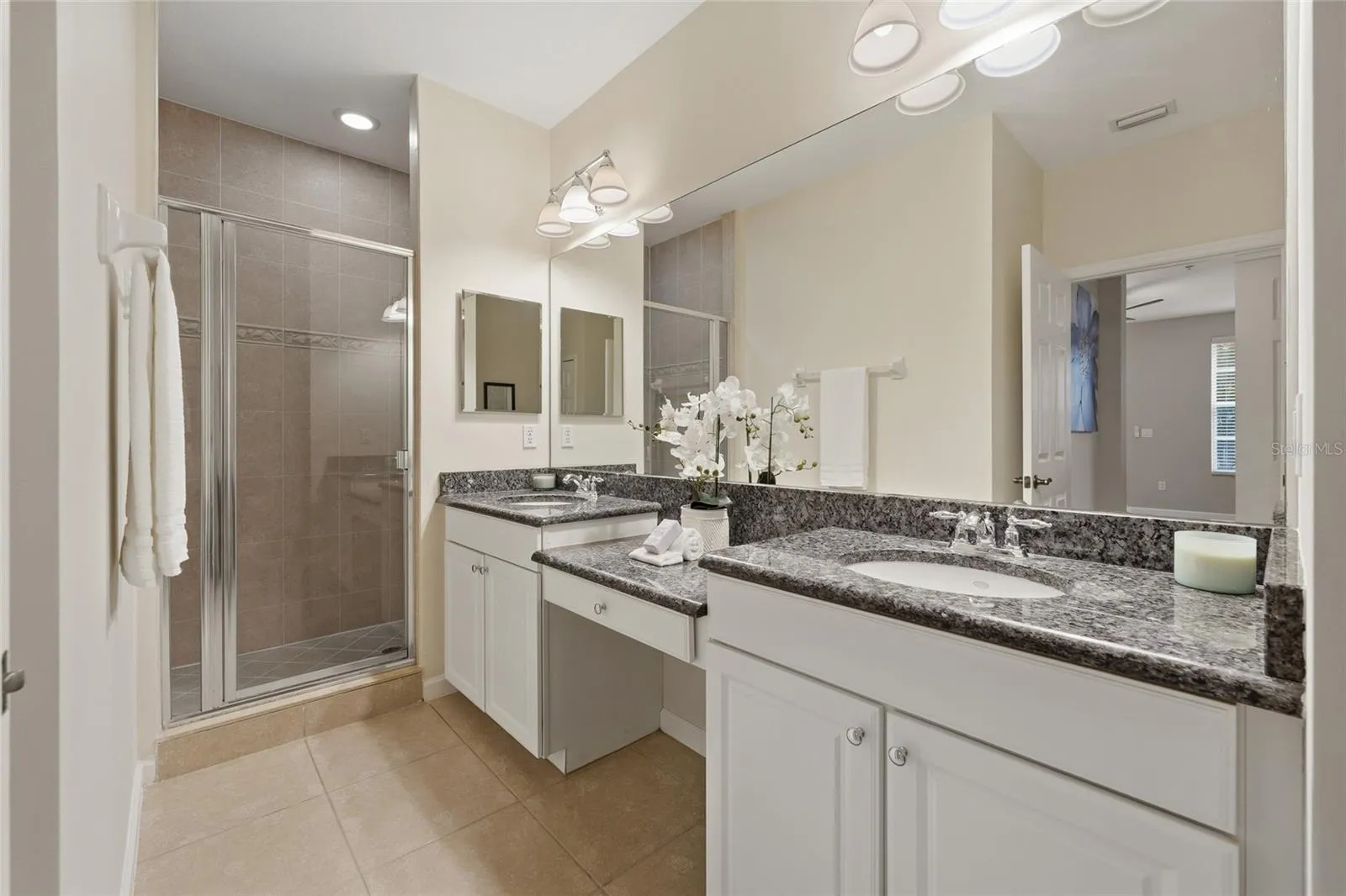 Primary bathroom features dual vanities, granite countertops, separate tiled shower and generous counter space.
