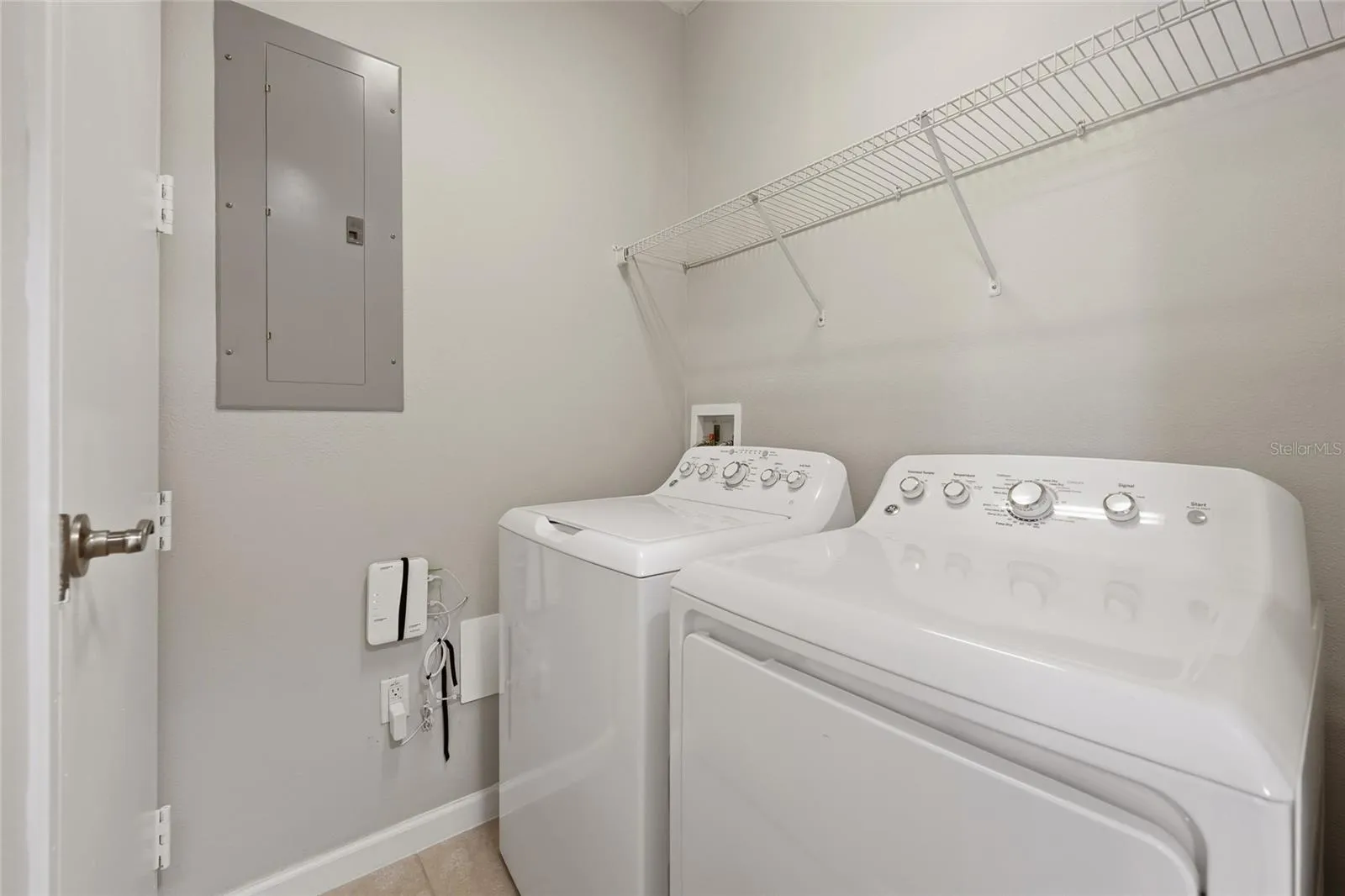 Convenient in-unit laundry room with full-size washer and dryer plus additional shelving.