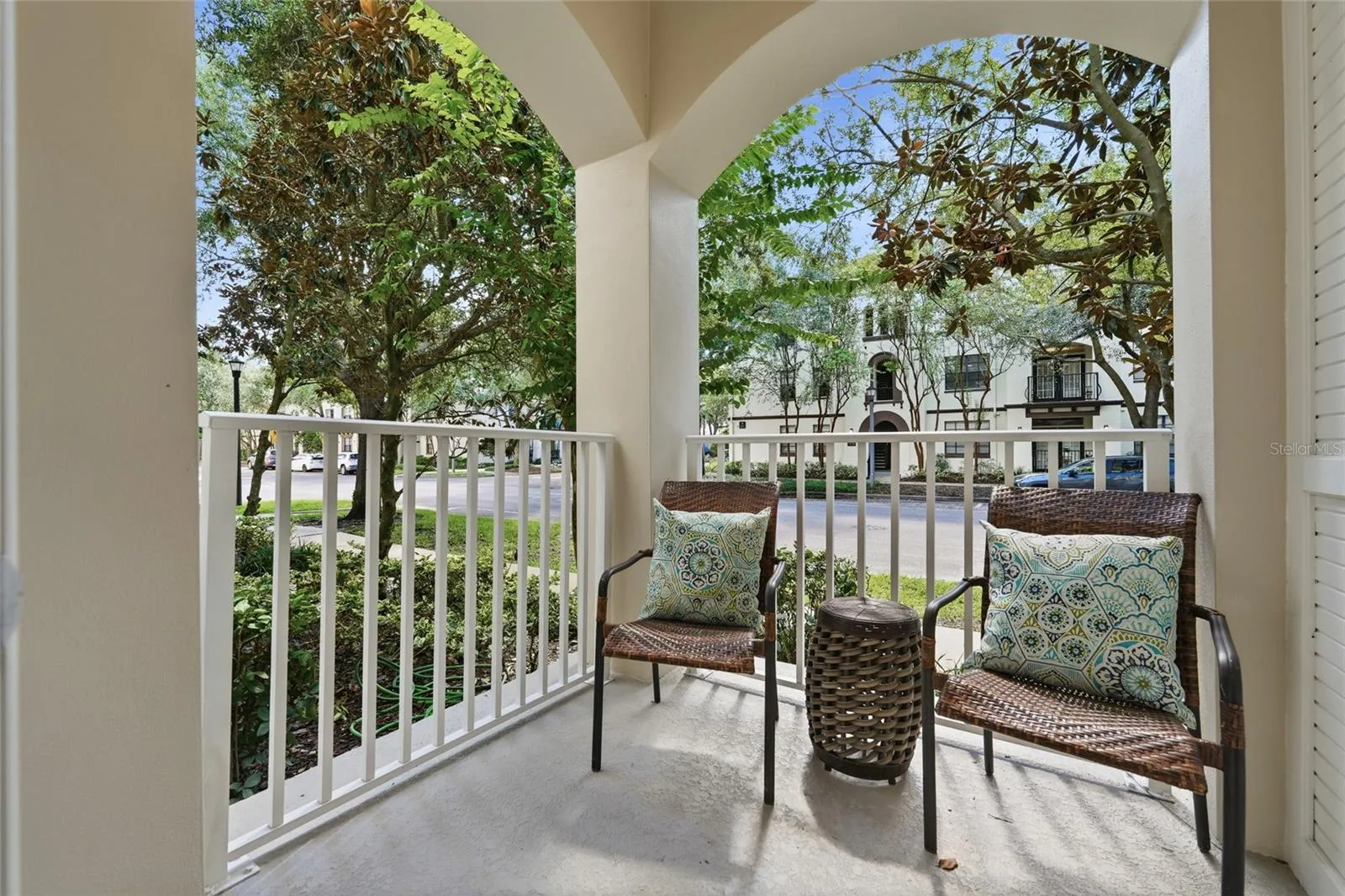 Private covered balcony off the primary suite offers a peaceful outdoor retreat surrounded by mature landscaping.