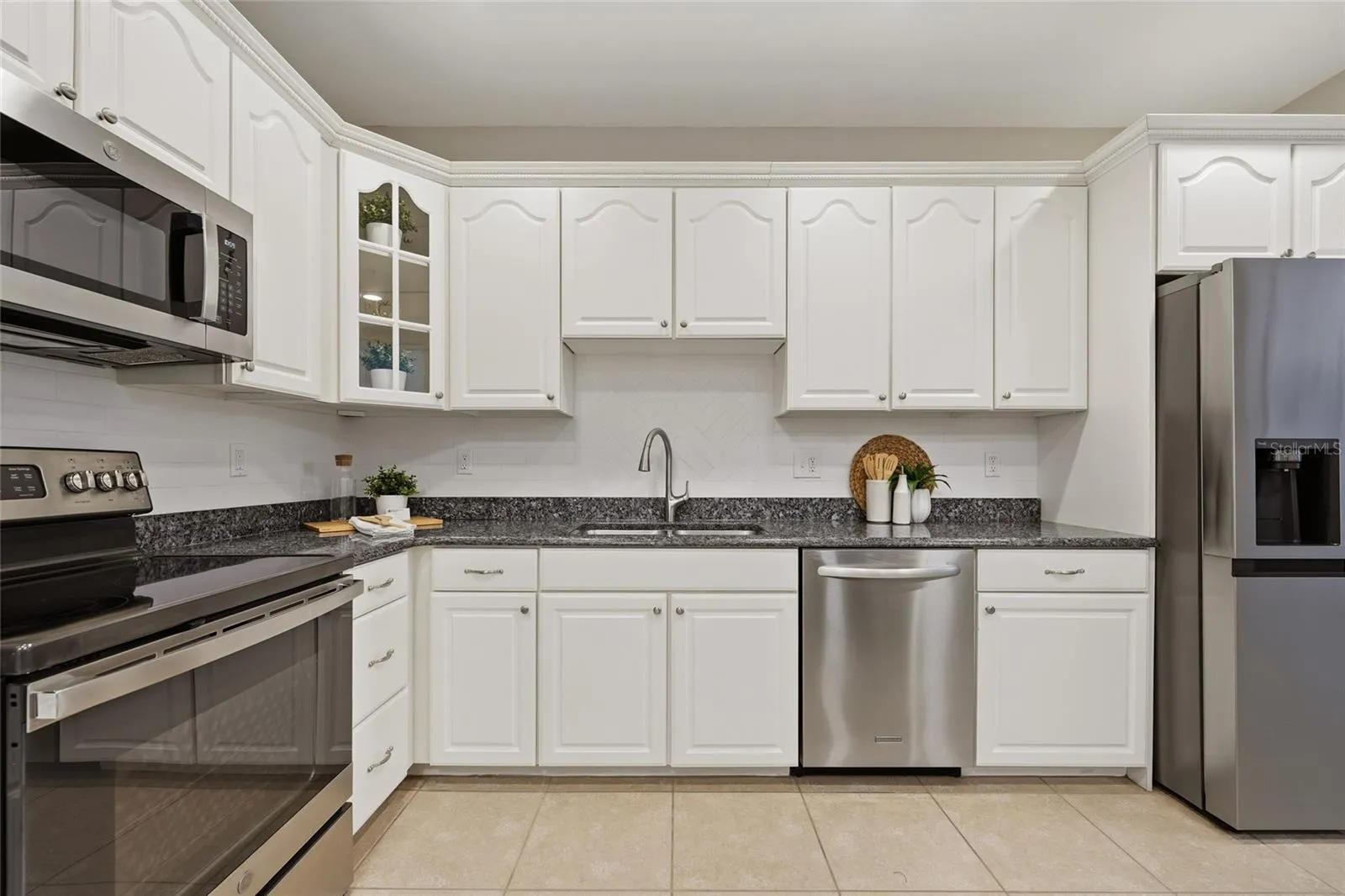 Crisp white cabinetry, granite countertops, tile backsplash and stainless-steel appliances complete the spacious kitchen.