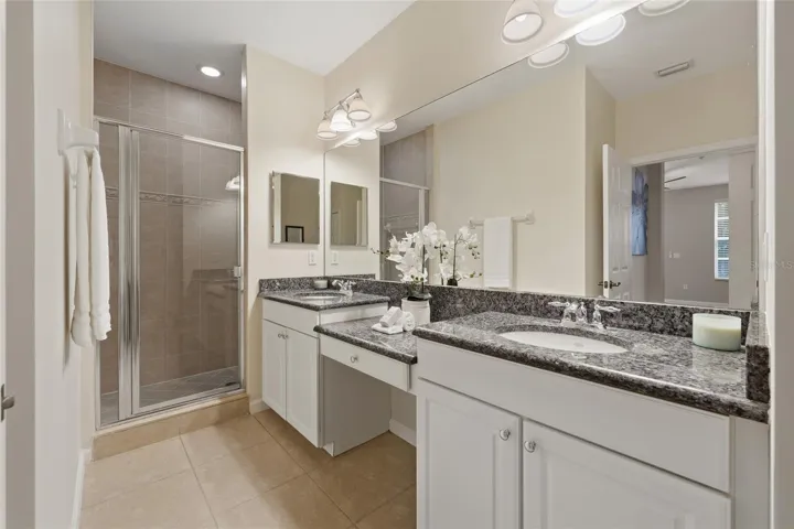 Primary bathroom features dual vanities, granite countertops, separate tiled shower and generous counter space.