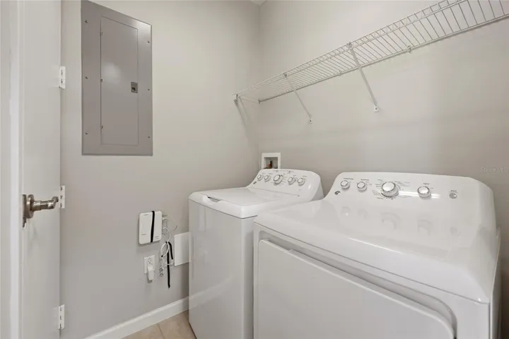 Convenient in-unit laundry room with full-size washer and dryer plus additional shelving.