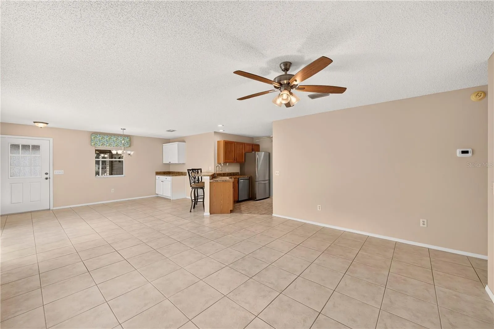 Standing in the corner of the living room looking toward the dining room and kitchen.