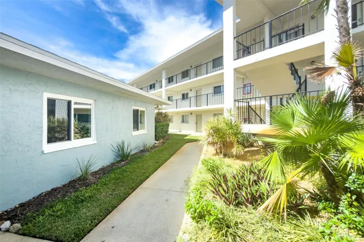 Walkway from covered parking surrounded by Tropical landscaping