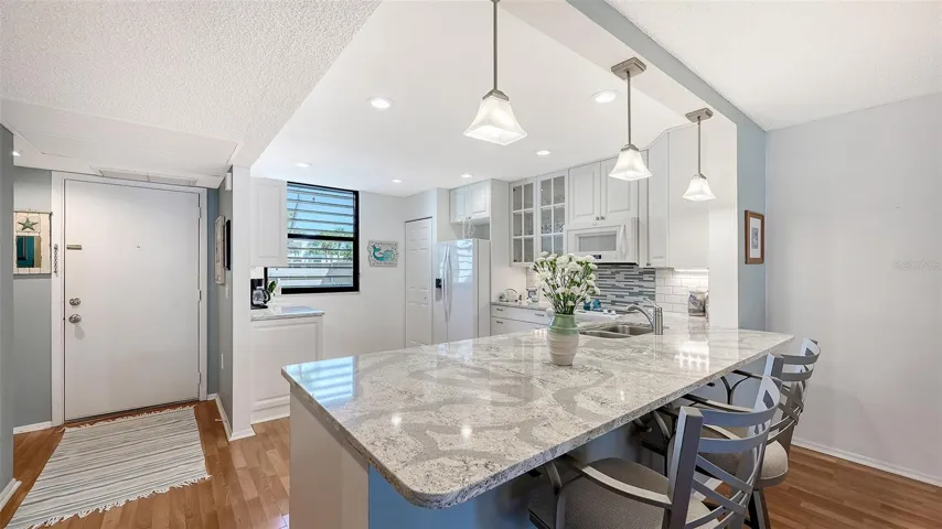 The updated open kitchen features breakfast bar, recessed lighting, and a tile backsplash.