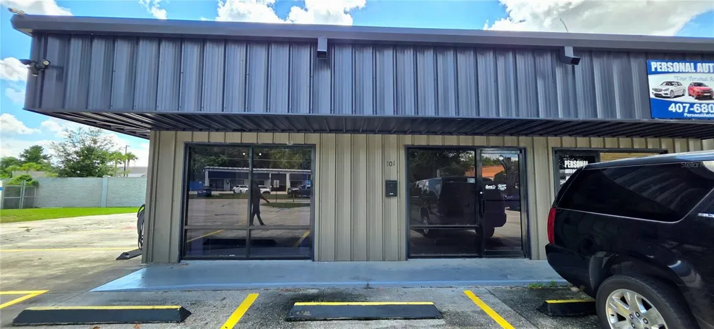 Front view of the offices with floor-to-ceiling windows and glass door. Shared customer parking on-site