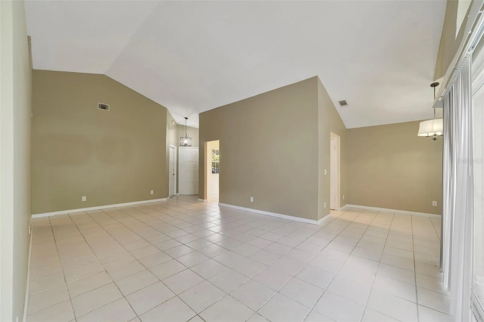 The spacious Living Room immediately catches your eye with its VAULTED CEILING, a unique decorative ledge and an ARCHED WINDOW positioned above the sliding glass doors that open to the back patio and SPACIOUS YARD, creating an easy connection between the indoor and outdoor spaces.