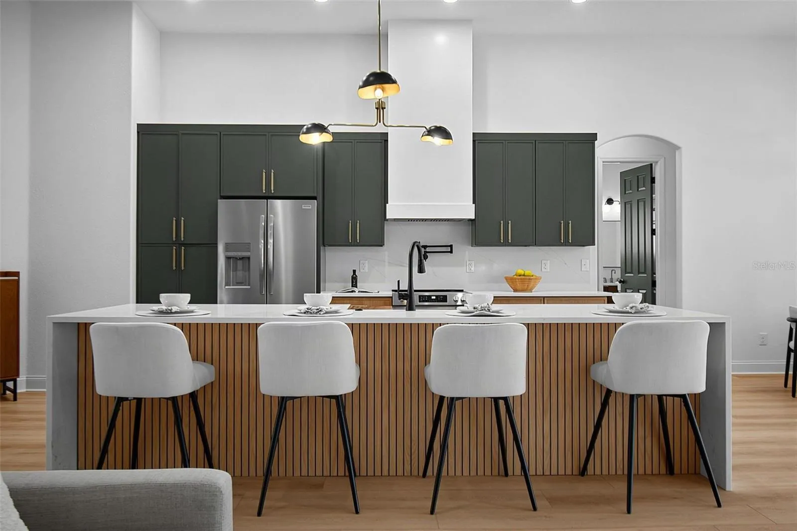 The kitchens centerpiece is the waterfall island in quartz countertop along with the sleek back wall featuring the beautiful tile backsplash, range, custom range hood along custom wood cabinets and quartz countertops.