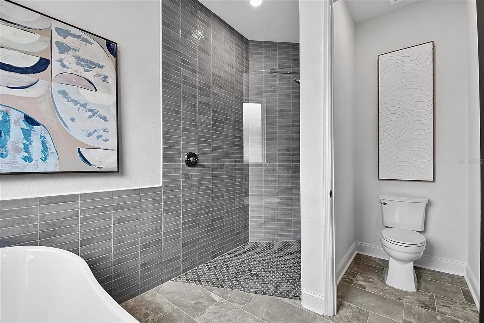 This shows the new glass surround tiled shower, private water closet and free standing tub