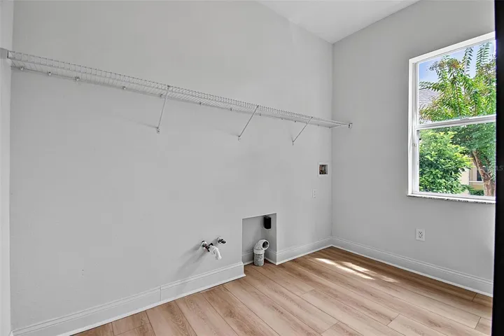 The laundry room shows the washer/dryer hookups along with shelving for storage and place to hang clother