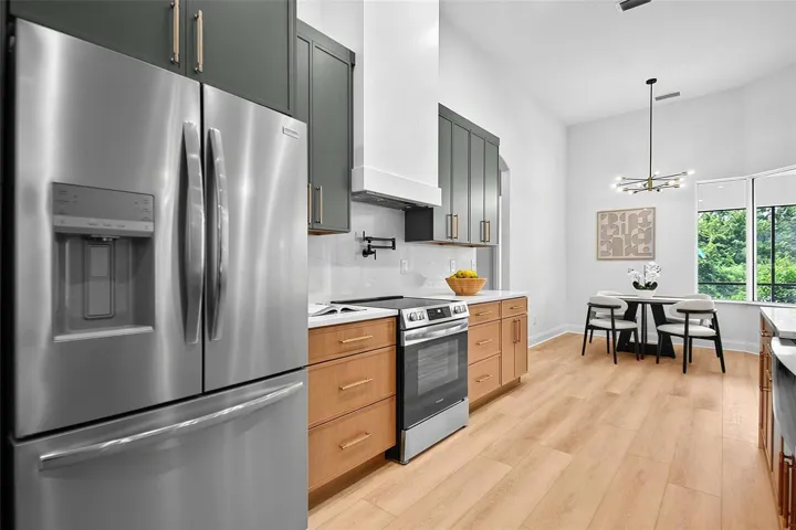Again, the refrigerator is framed with custom design of the wood cabinets, range, and custom range hood.