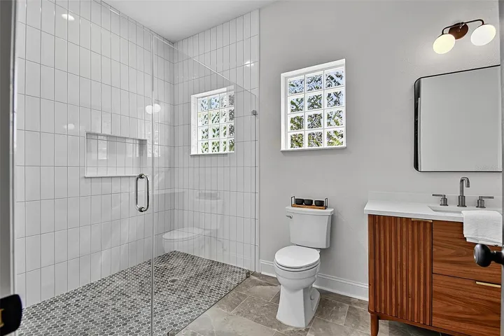 The 2nd guest bathroom is so spacious , it has a huge tiled shower with niches, a block with giving natural light, new toilet, new mirror, lighting and a wood vanity with solid stone countertops.