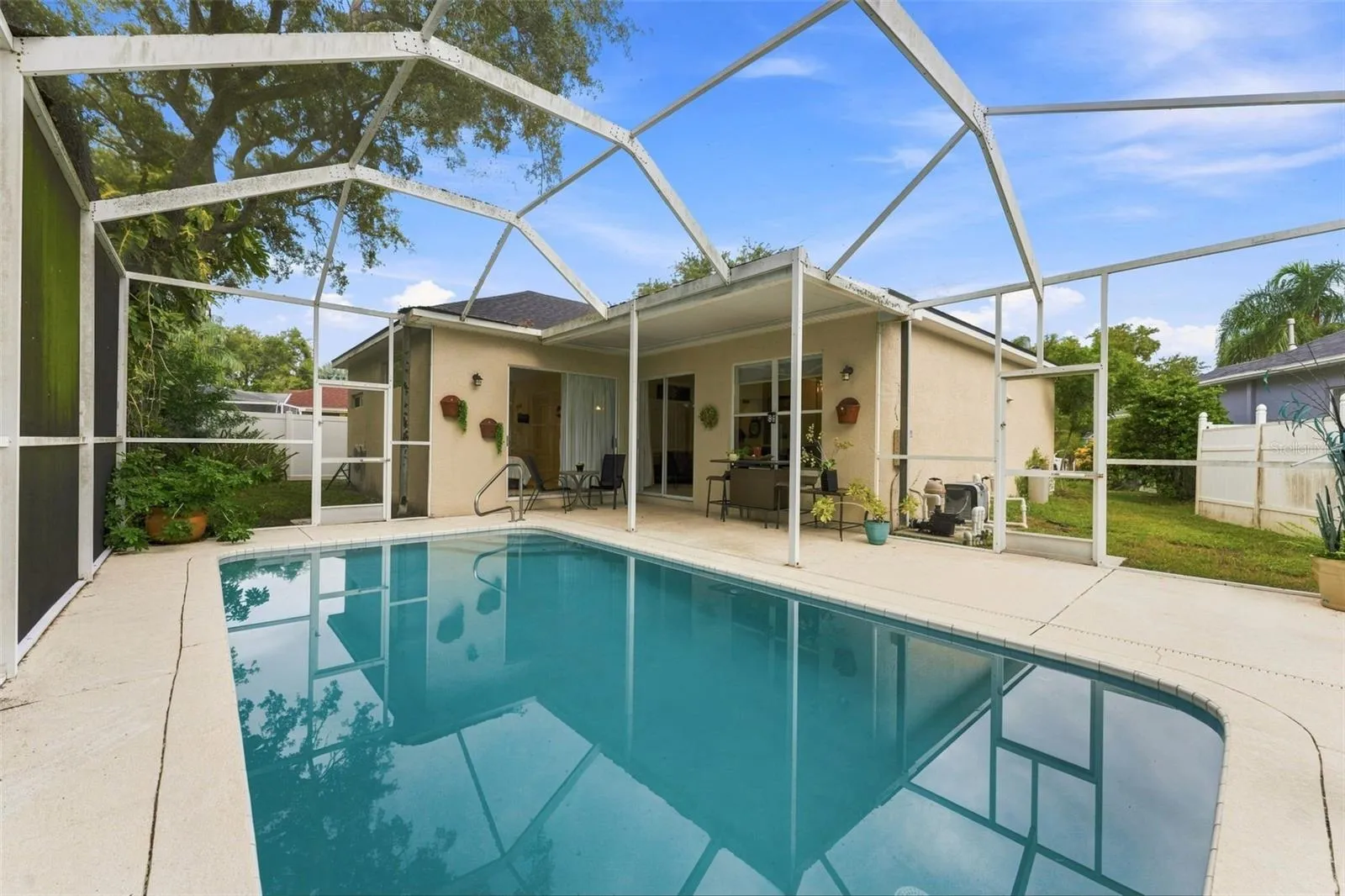 Tarpon Springs Pool Home, covered patio and large yard surrounding the space.
