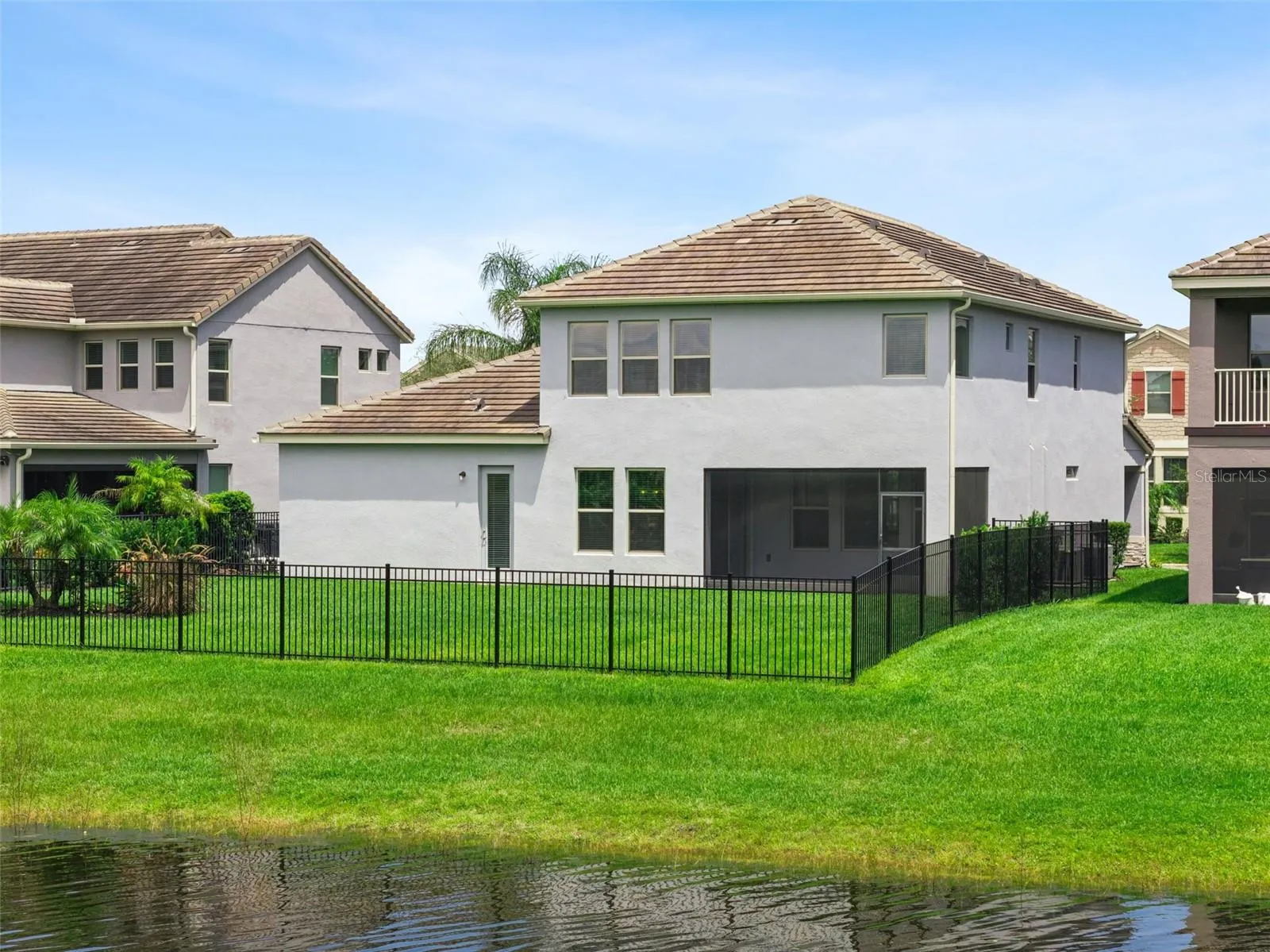 Rear exterior with fenced backyard and pond frontage