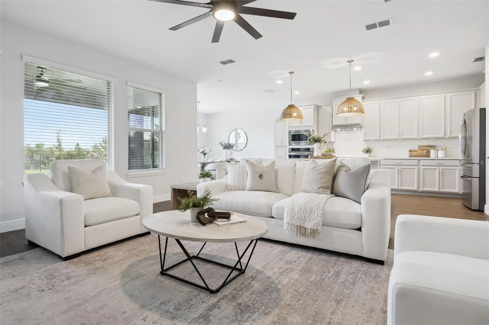 Open-concept living room and kitchen with wood-look tile and pond-view windows