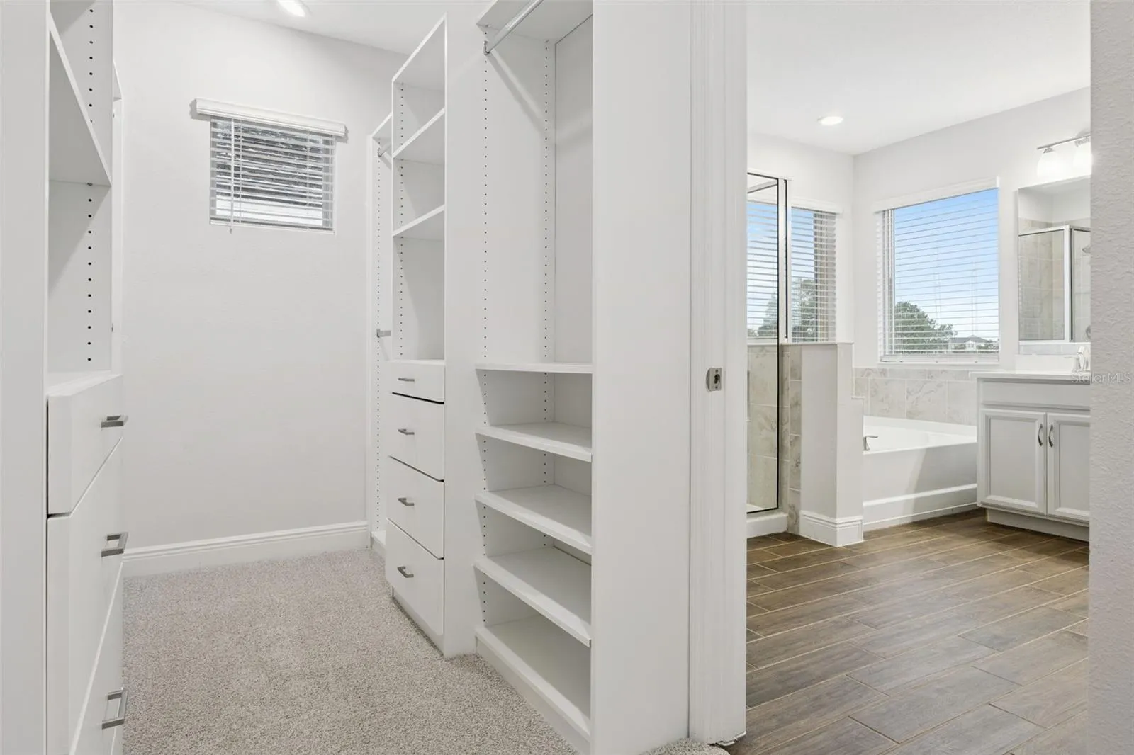 Walk-in closet with built-in shelving connecting to the primary bath