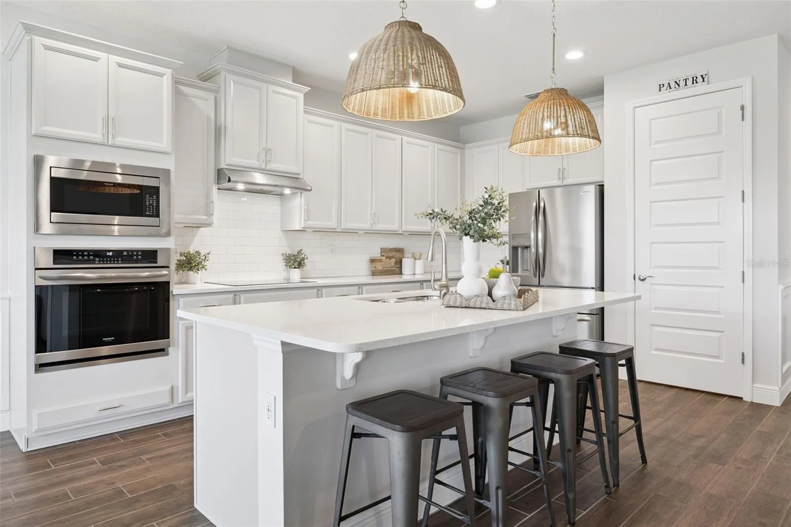 Kitchen with double wall ovens, breakfast bar island, and walk-in pantry