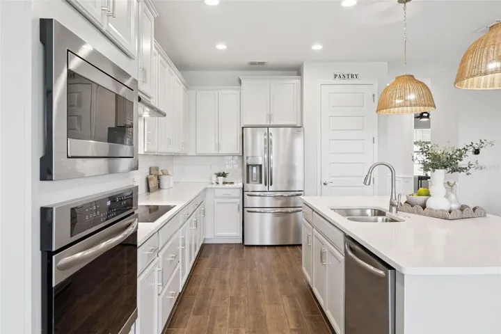 Kitchen with stainless appliances, quartz counters, and range hood vented outside