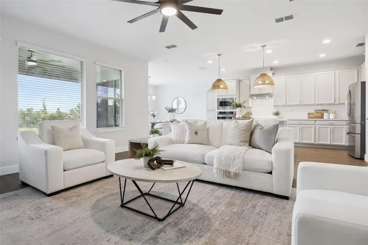 Open-concept living room and kitchen with wood-look tile and pond-view windows