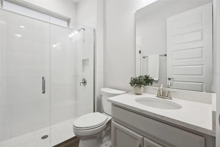 First-floor full bath with walk-in shower and quartz-topped vanity