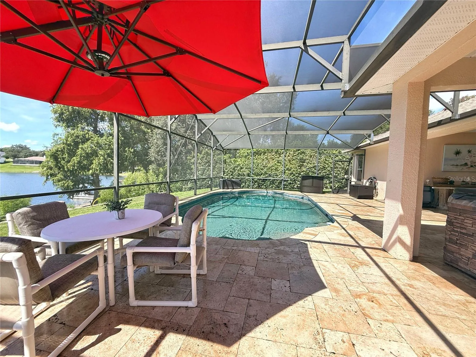 Additional view of the pool area and lake view. Travertine flooring, covered lanai and screened in. Pool bath access.