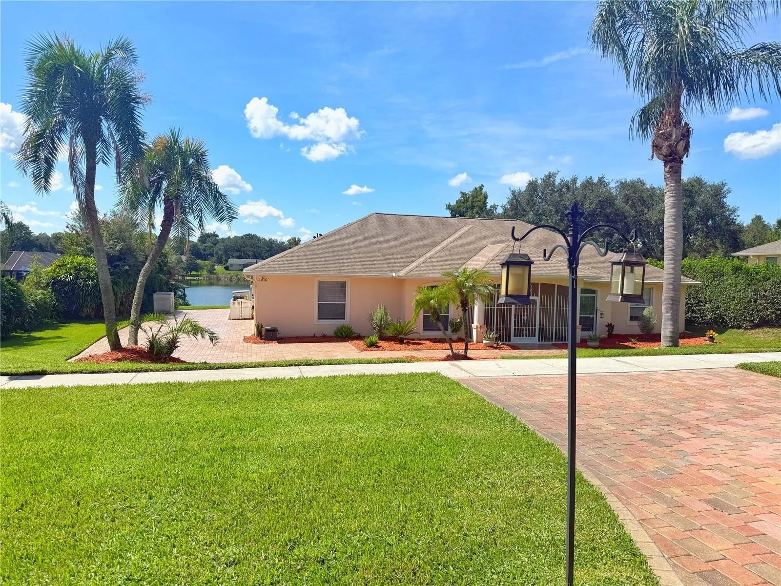 Front Exterior with freshly sealed paver driveway, gutters, screened in and covered front entry. Lake front with a dock.