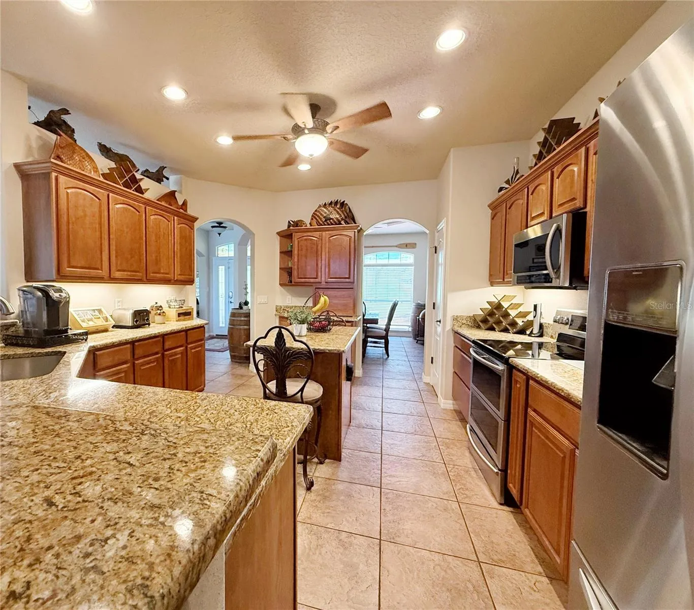 Kitchen view from Dinette, ceramic tile flooring, granite countertops, solid wood cabinets with under lighting, closet pantry, recessed lighting, stainless steel appliances