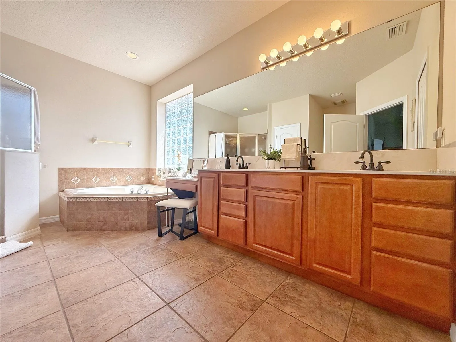 Primary Bathroom with vanity space, dual sinks, ceramic tile flooring, shower and separate garden tub.