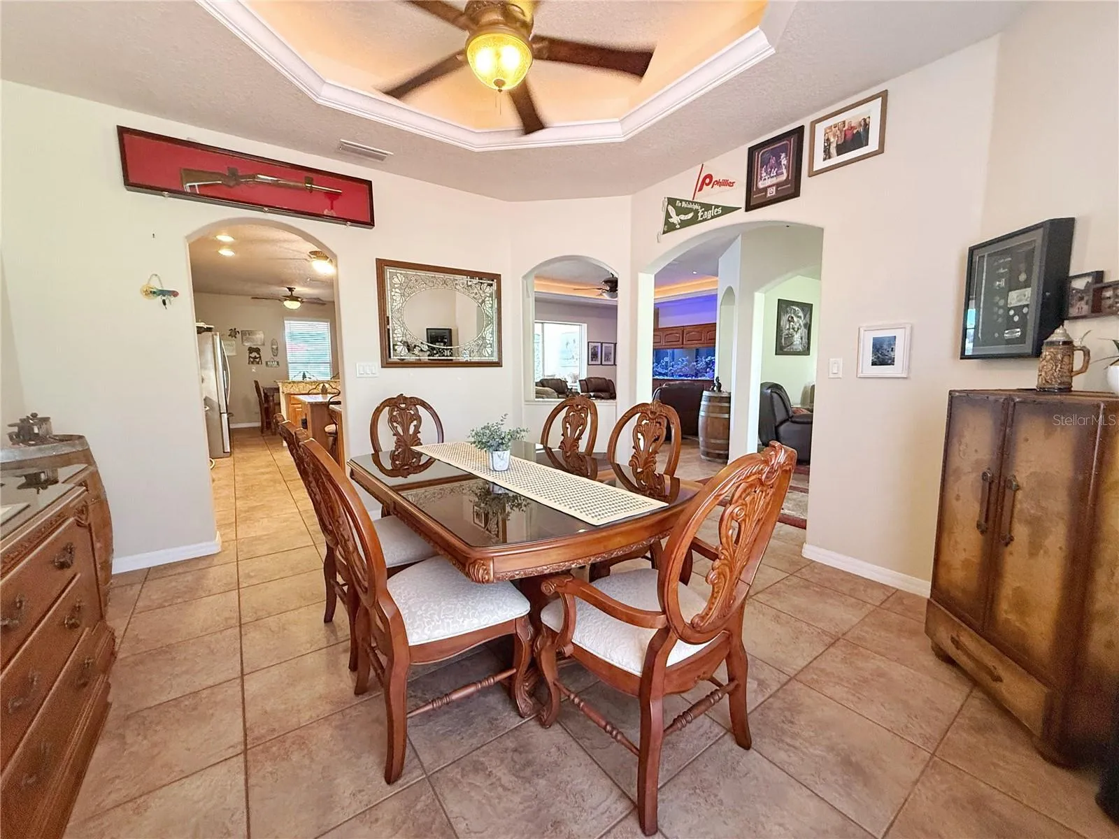 Dining room with Kitchen, Living and Family room in background. Tray ceiling with ambient lighting , ceramic tile flooring