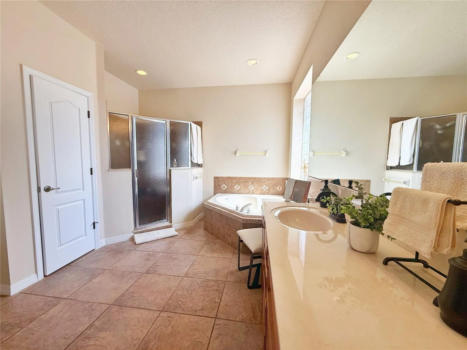 Additional view of the Primary Bathroom with Garden tub, separate shower, dual sinks, vanity space, ceramic tile flooring, walk in closet