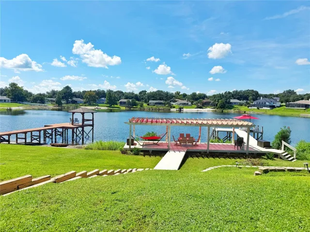 Rear yard with lake view. Covered and open Dock with fishing pier and ladder to climb in and out of the water.