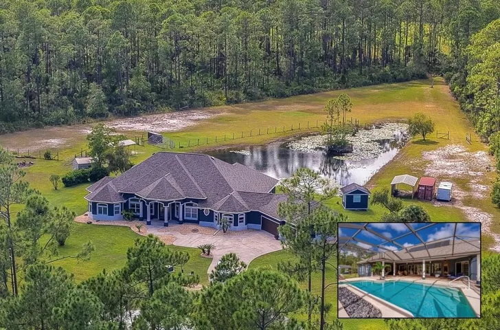 Expansive private home surrounded by dense green forest, a scenic pond, and a long paved driveway.
