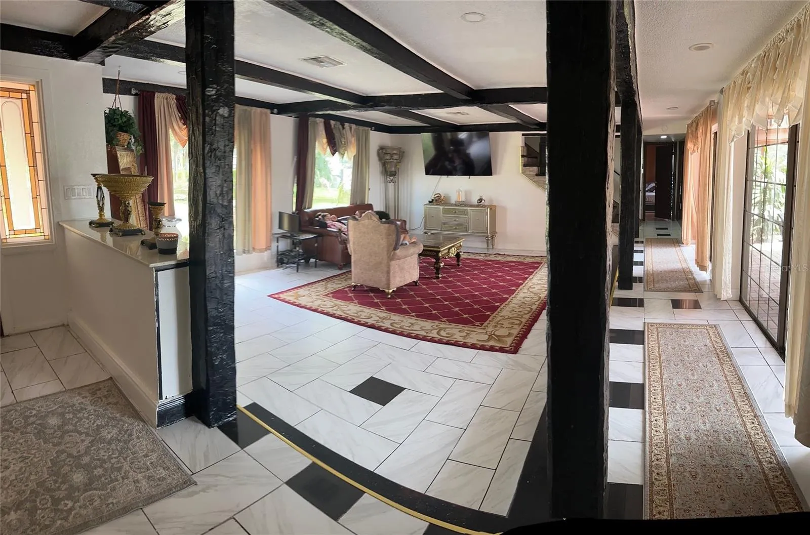 STEP DOWN TO LARGE LIVING ROOM . DOORS TO POOL AREA. HALLWAY TO LIBRARY, 1/2 BATH  AND STAIRWAY TO 4 BEDROOMS AND 3 BATHROOMS