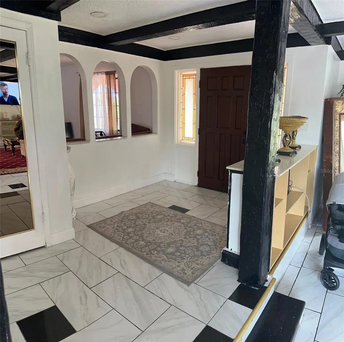 FOYER. ARCHED OPENING SHOWING TV/2ND LIVING ROOM/OFFICE
