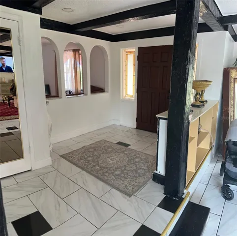 FOYER. ARCHED OPENING SHOWING TV/2ND LIVING ROOM/OFFICE