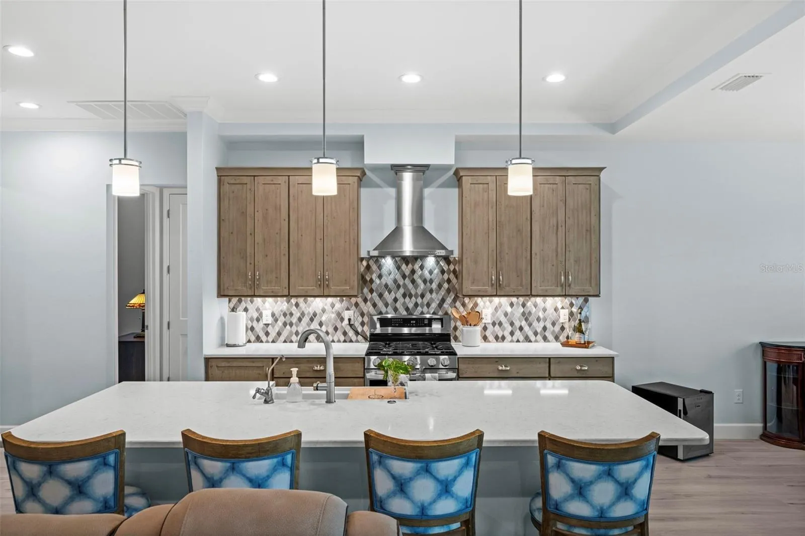 The large quartz island is glistens. The pendant lighting adds additional sheen.