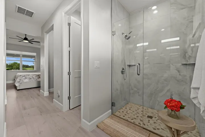 Floor to ceiling tile surrounds this glass enclosed shower.