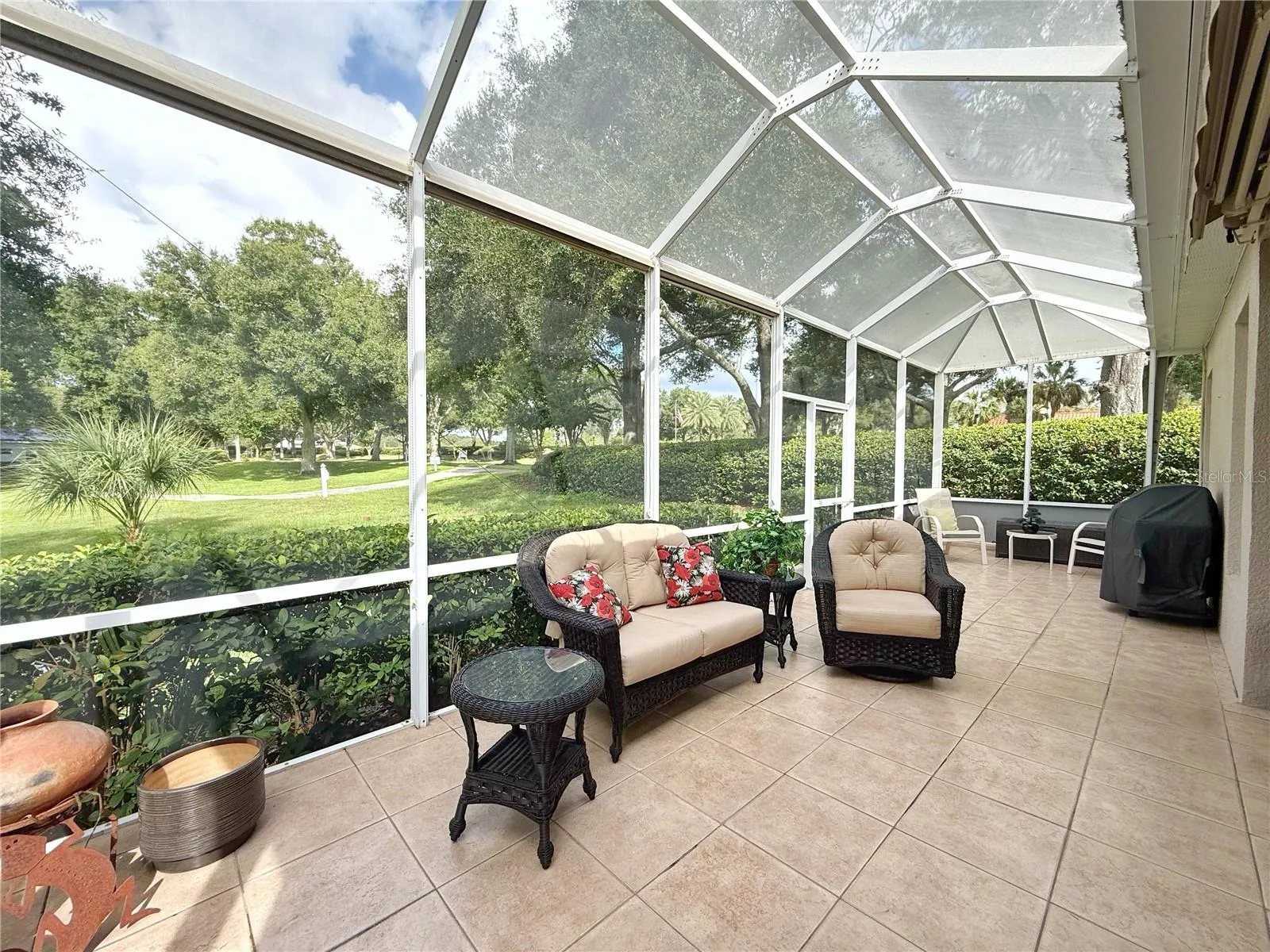 Rear lanai with extended cage with ceramic tile flooring, extending cage, retractable awning, windows in the covered area and view of golf course.