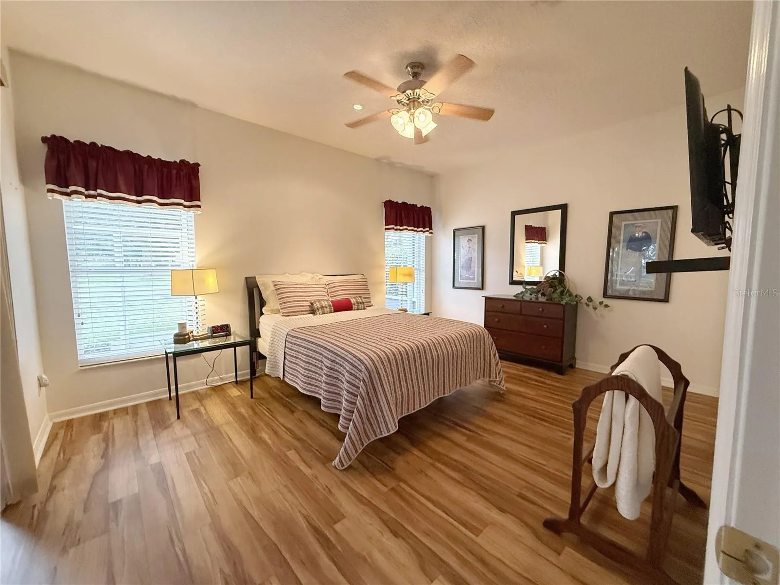 Primary Bedroom with golf view,  sliding glass doors onto the covered and screened in lanai, laminate flooring, en suite bathroom, walk in closet
