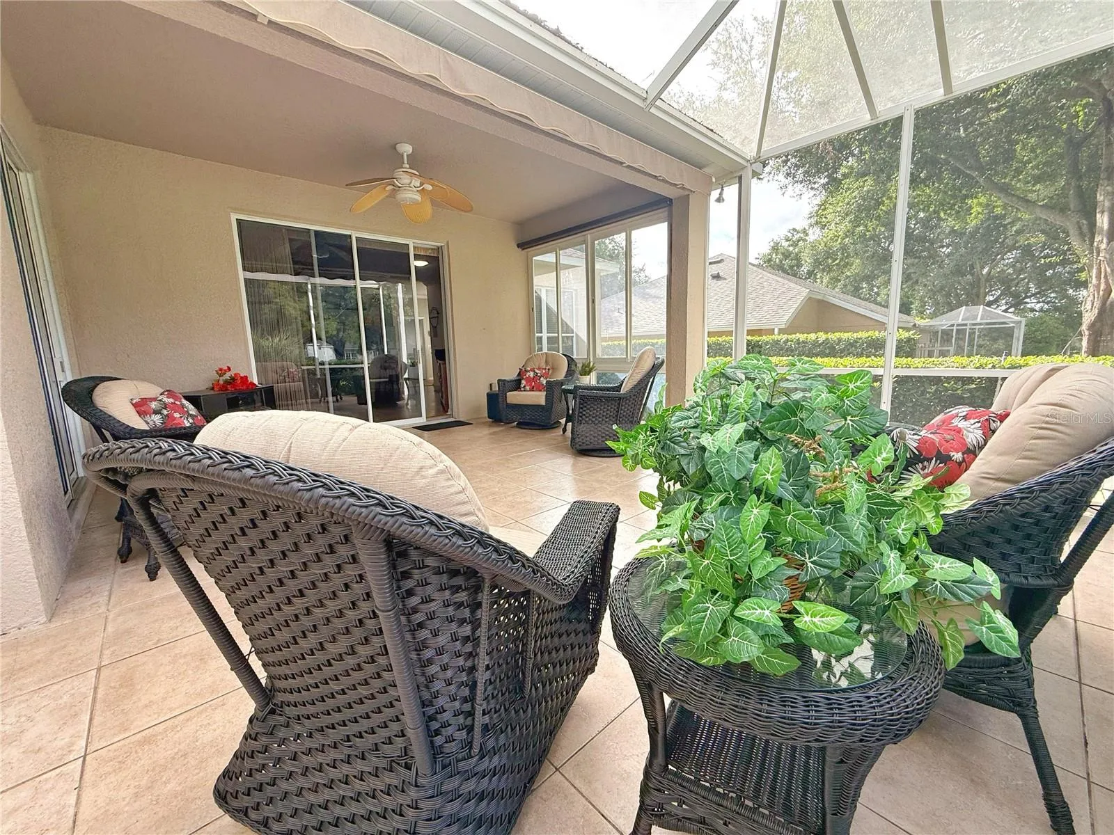 Rear covered and screened in lanai with ceramic tile flooring, extending awning, ceiling fan , sliding glass doors into Living room and Primary Bedroom and golf course view.
