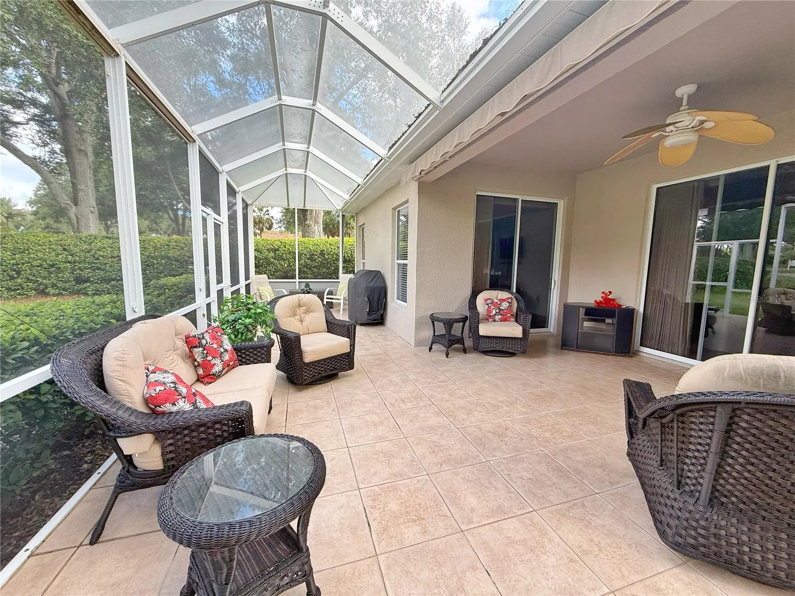 Additional lanai view with extended cage, ceramic tile flooring and sliding glass doors onto into the Living Room and Primary Bedroom
