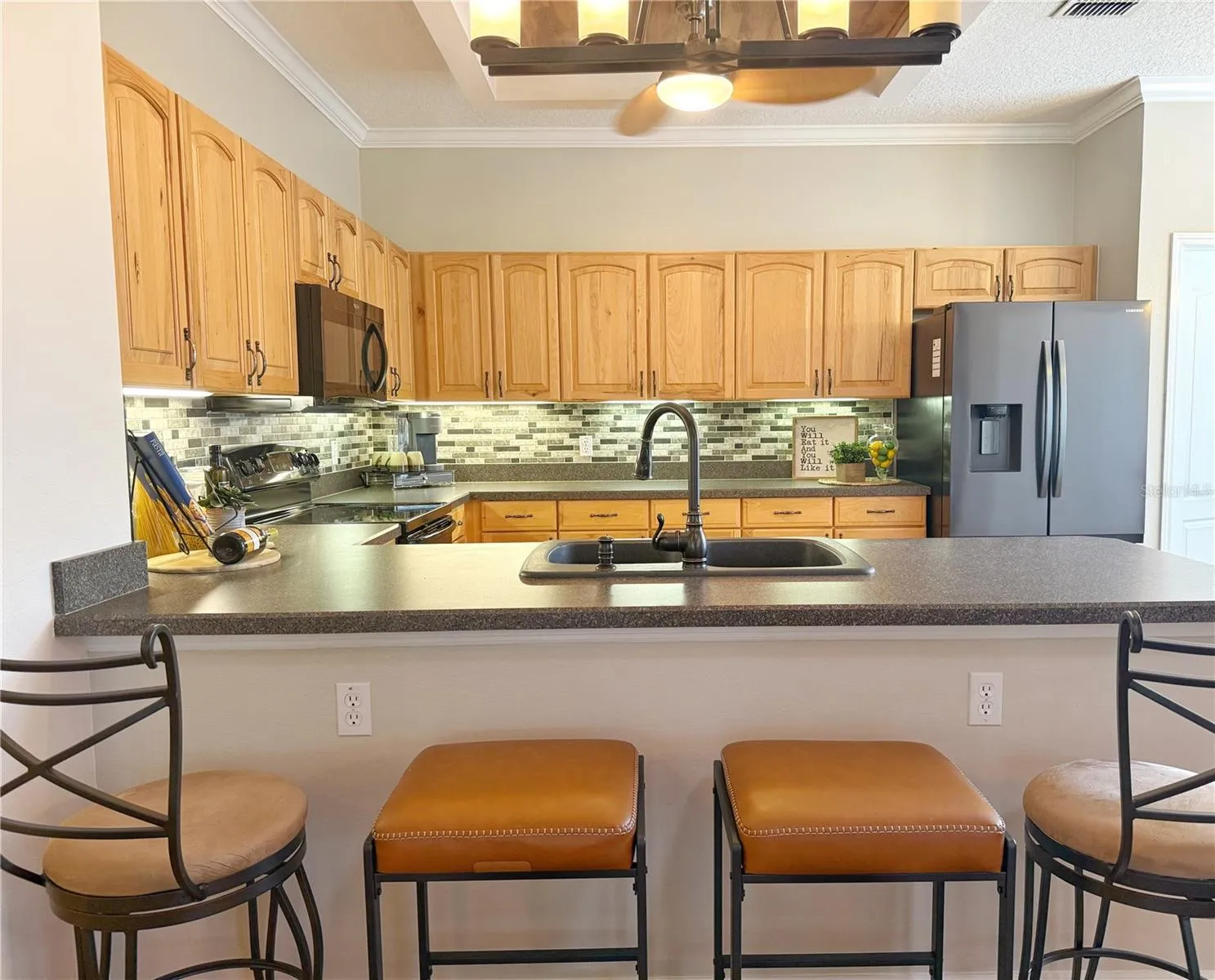 Kitchen with solid wood cabinets with under cabinet lighting, stainless steel appliances,backsplash, crown molding, laminate flooring, closet pantry, dinette and bar top seating, updated fixtures