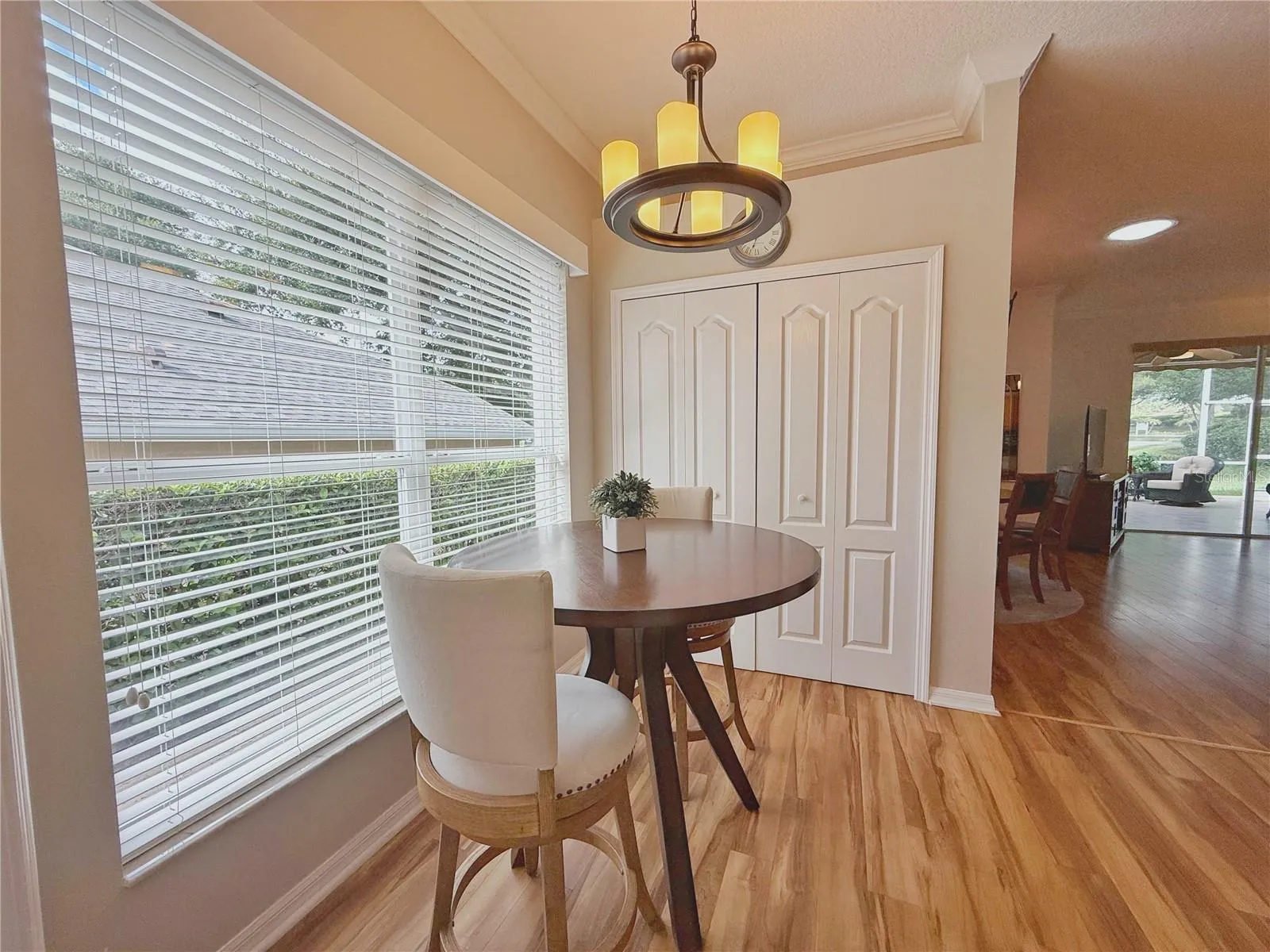 Additional Dinette view with Dining and Living Room in background, laminate flooring, crown molding, decorative shelf, closet pantry