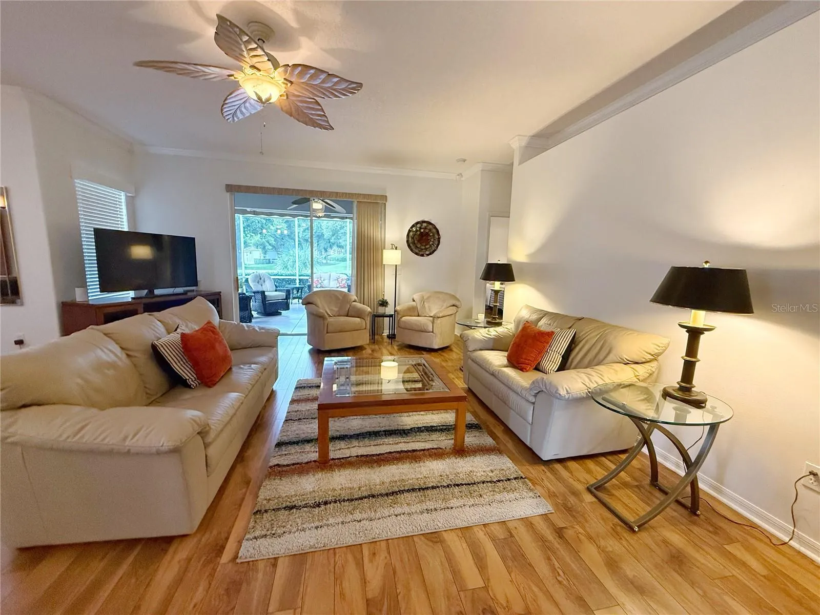 Living room with Laminate flooring, crown molding, sliding glass doors onto the Covered and screened in lanai with Golf course view, open floor plan