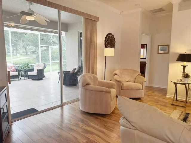 Additional view of Living Room with view of Primary bedroom and lanai in background. Sliding glass doors leading onto the covered and screened in lanai and Golf Course view.