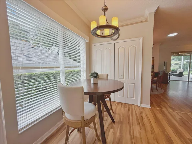 Additional Dinette view with Dining and Living Room in background, laminate flooring, crown molding, decorative shelf, closet pantry